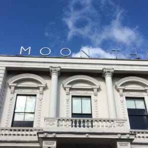 A photo of Half Moon Theatre taken during the day with bright blue skies .On the roof of the big, white, building with a balcony and pillars, are written the words Half Moon Theatre.